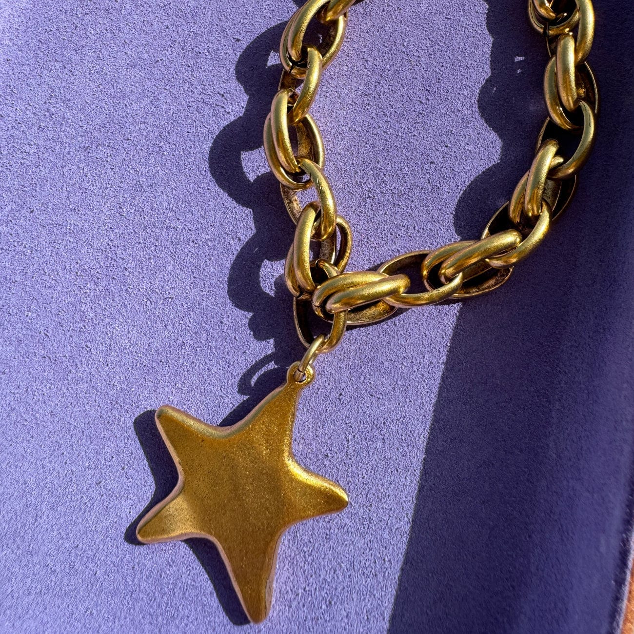 Gold chain necklace with a star pendant on a purple background