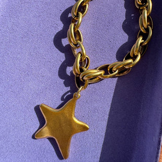 Gold chain necklace with a star pendant on a purple background