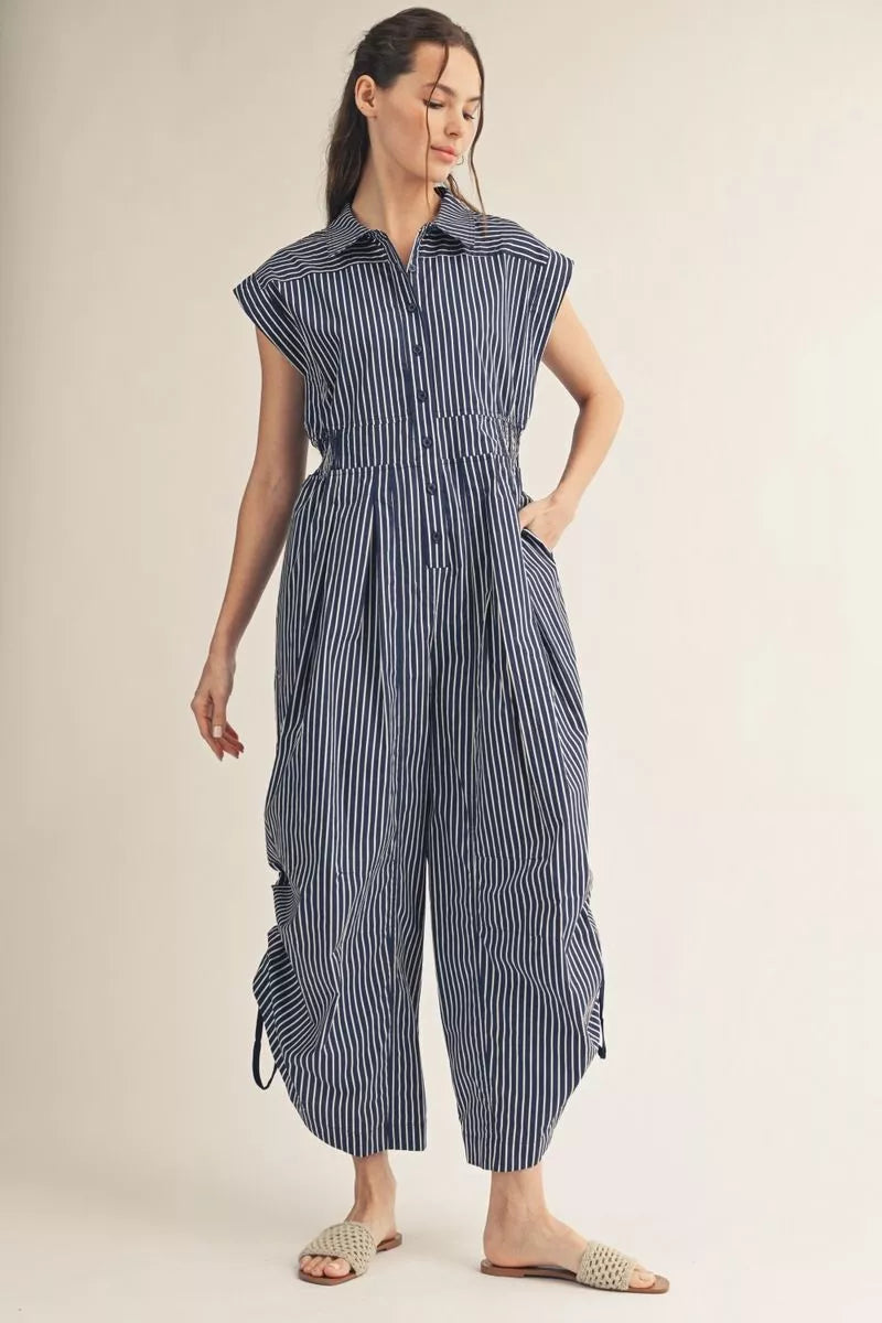 Woman wearing a blue and white striped jumpsuit on a beige background
