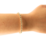 Gold bracelet on a wrist against a white background