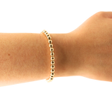 Gold bracelet on a wrist against a white background