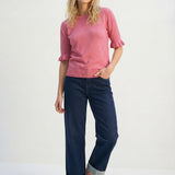 Woman wearing a pink sweater and blue jeans on a white background