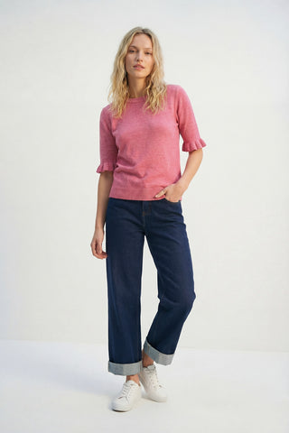 Woman wearing a pink sweater and blue jeans on a white background