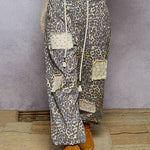 Person wearing patterned pants with patches and orange boots on a textured floor.