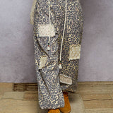 Person wearing patterned pants with patches and orange boots on a textured floor.