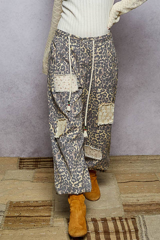 Person wearing patterned pants with patches and orange boots on a textured floor.