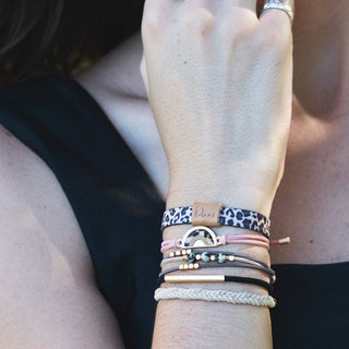 Close-up of a wrist wearing multiple bracelets with a blurred background