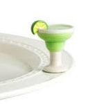 Green cocktail glass with a lime wedge on a white plate