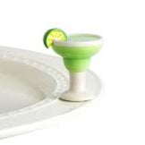Green cocktail glass with a lime wedge on a white plate