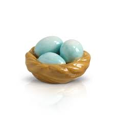 Small wooden basket with three turquoise eggs on a white background