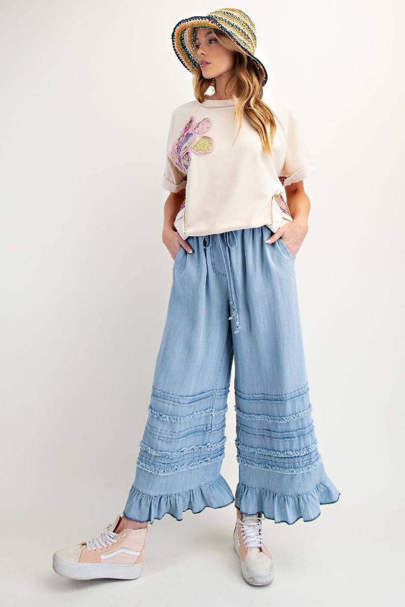 light blue pant with ruffle and gril with hat and cream tee and sneakers