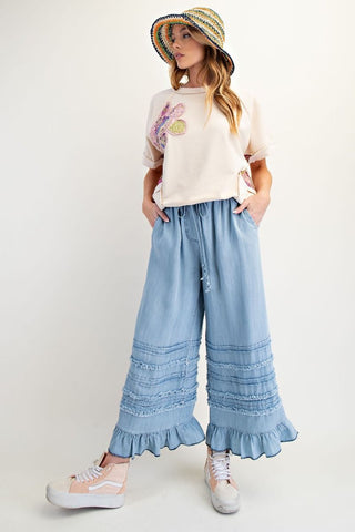 light blue pant with ruffle and gril with hat and cream tee and sneakers