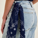 Navy blue bandana with white patterns tied around a person's waist, wearing light blue jeans.