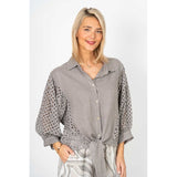 Woman wearing a gray shirt with lace details on a white background