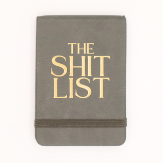Gray notebook with 'The Shit List' in gold on a white background