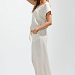 Woman wearing a white dress with black Adidas shoes on a light gray background