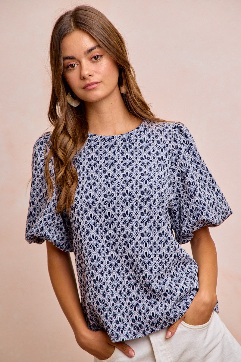 Woman wearing a blue floral blouse against a beige background