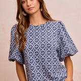Woman wearing a blue floral blouse against a beige background