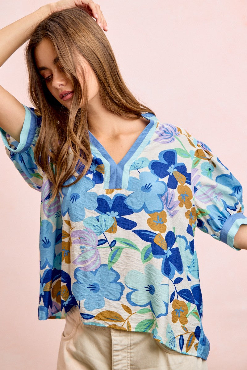 Woman wearing a colorful floral blouse against a pink background