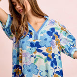 Woman wearing a colorful floral blouse against a pink background