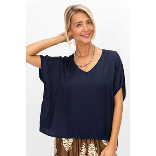 Woman wearing a navy blue top with a plain background