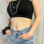Person wearing a black strapless top and blue jeans with a neutral background