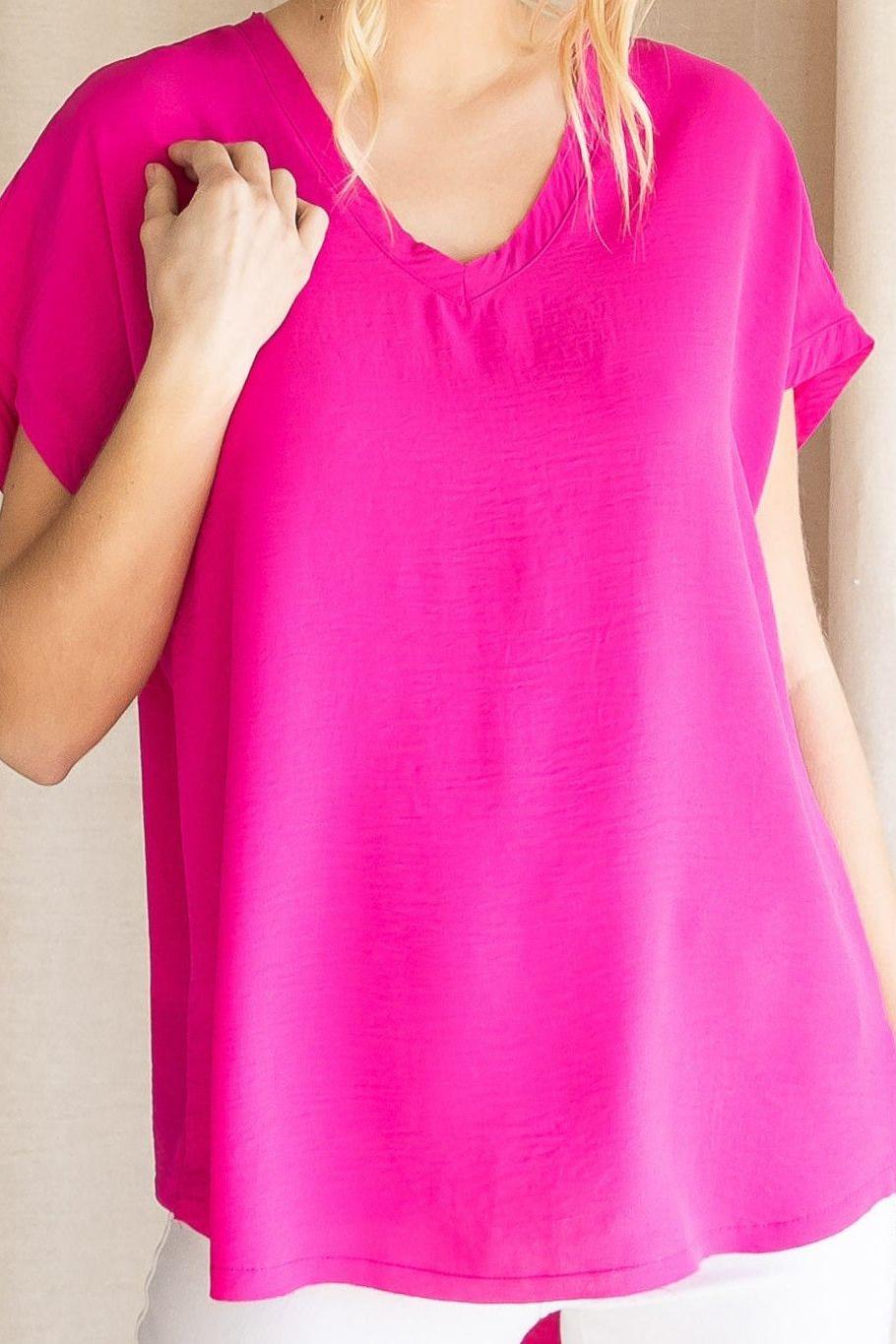 A model wearing a short-sleeved hot pink top with a round neckline and raw edge hems.