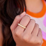 Close-up of a hand wearing a gold ring with a colorful background