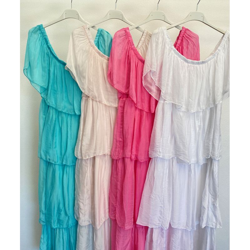 Four dresses in teal, pink, white, and red hanging on a rack against a white wall.