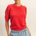 Person wearing a red shirt and blue jeans on a plain background
