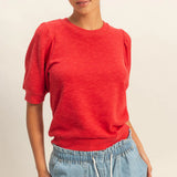 Person wearing a red shirt and blue jeans on a plain background