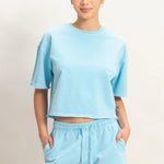 Person wearing a light blue t-shirt and shorts set on a plain background