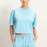 Person wearing a light blue t-shirt and shorts set on a plain background