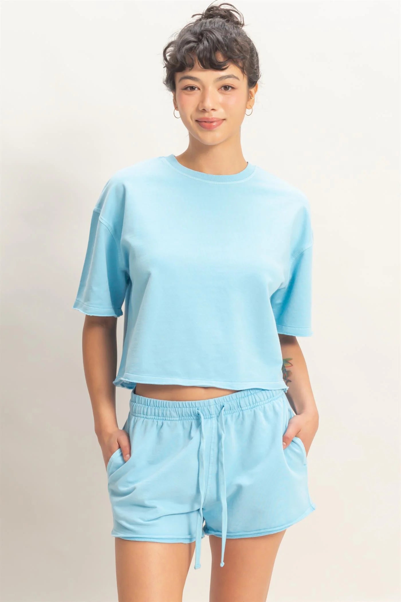 Person wearing a light blue t-shirt and shorts set on a plain background