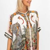 Woman wearing a patterned shirt with animal designs on a white background