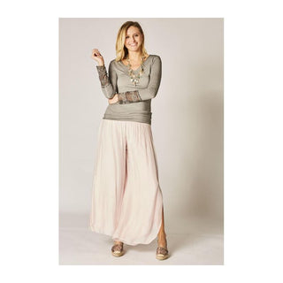 Woman wearing a long gray top and light pink skirt against a plain background