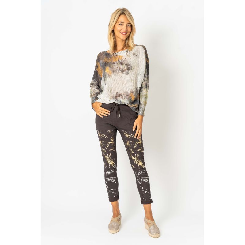 Woman wearing a patterned top and black leggings on a white background