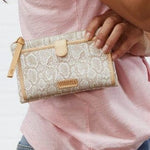 Person holding a patterned clutch bag with a visible brand name.