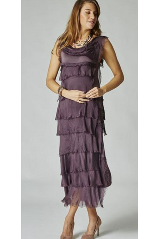 A woman wearing a purple silk ruffle dress with a V-neck neckline and sleeveless top. The dress features a tiered design with a longer hem in front.