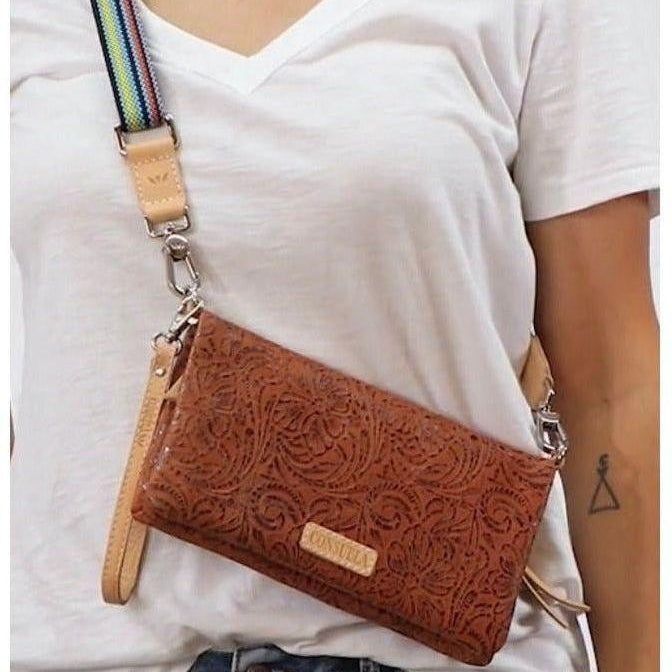 Brown leather handbag with intricate patterns worn over a white shirt